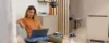 Una donna è seduta su un divano con un laptop in un soggiorno moderno. Nolte Living.