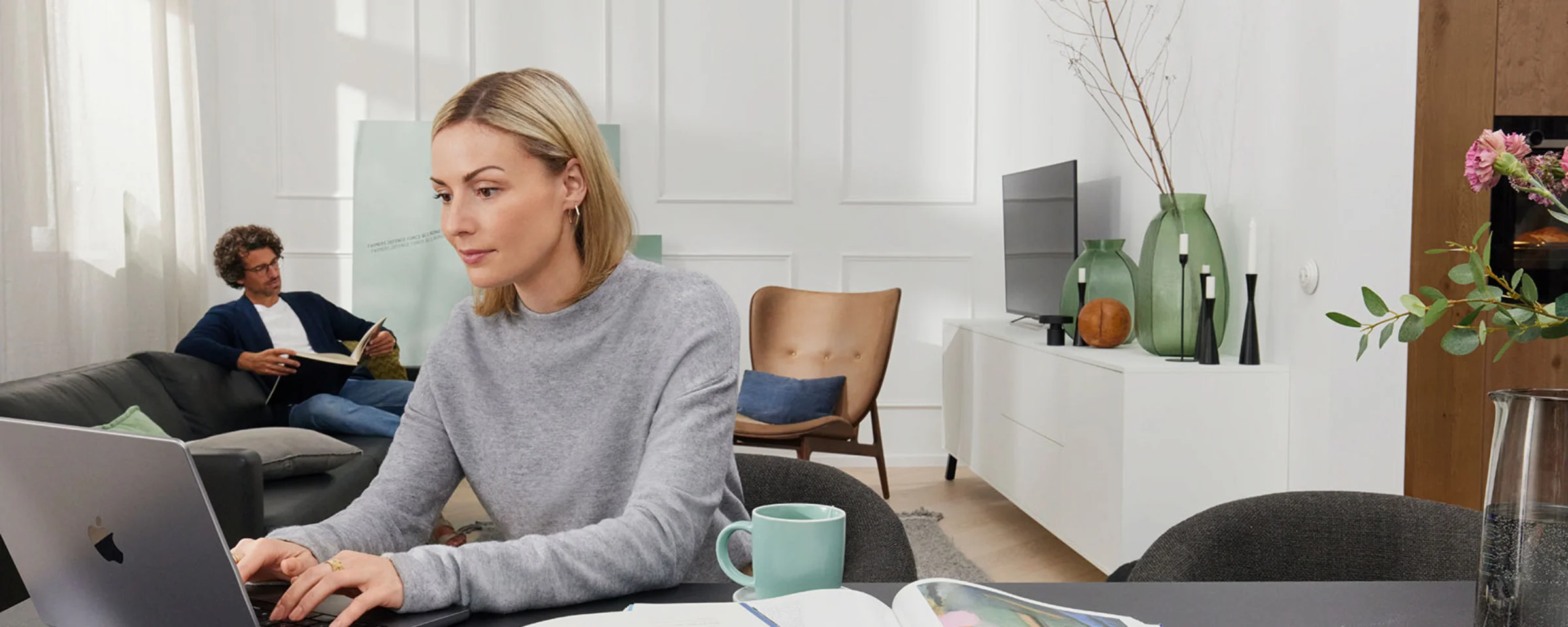 Due persone lavorano in un soggiorno moderno con mobili Nolte Living.