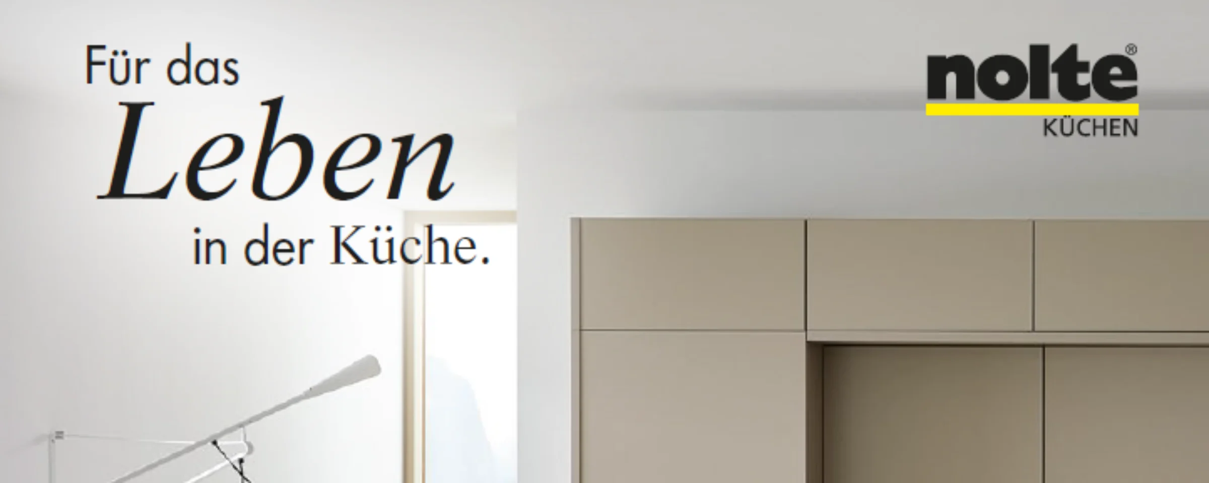 Cucina moderna con armadi chiari e grande finestra, elegantemente presentata da Nolte Kitchen.