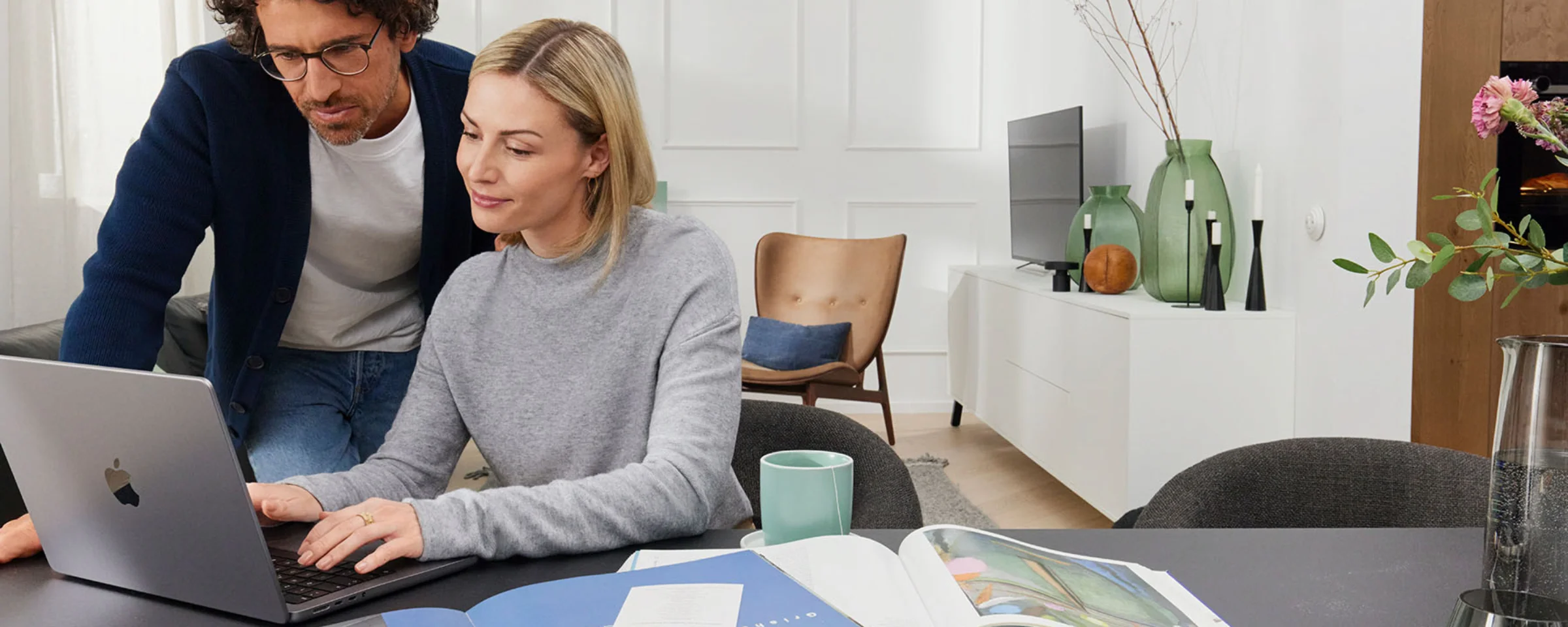 Una coppia lavora insieme su un laptop in un soggiorno moderno con arredamento Nolte Living.