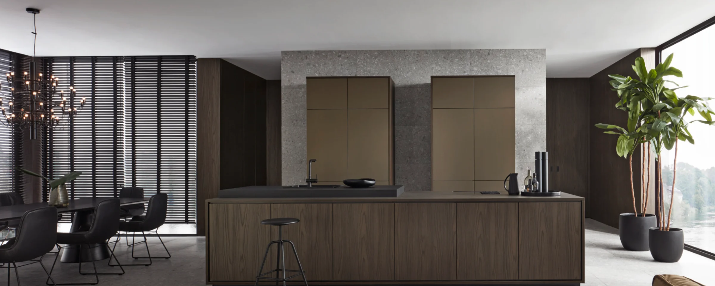 Cucina moderna con isola, tavolo da pranzo e piante, elegantemente arredata da Nolte Kitchen.