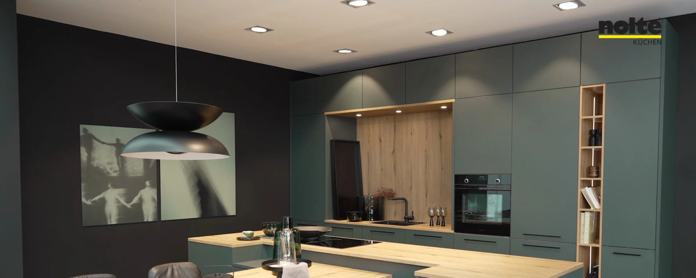 Cucina moderna con armadi verdi e piani in legno, arredata da Nolte Kitchen.