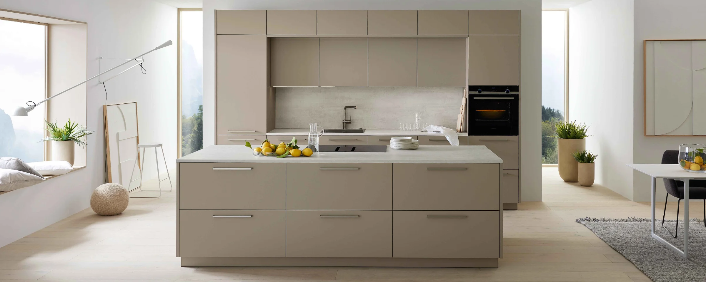 Cucina moderna con grande isola e armadi chiari, circondata da ampie finestre, Nolte Kitchen.