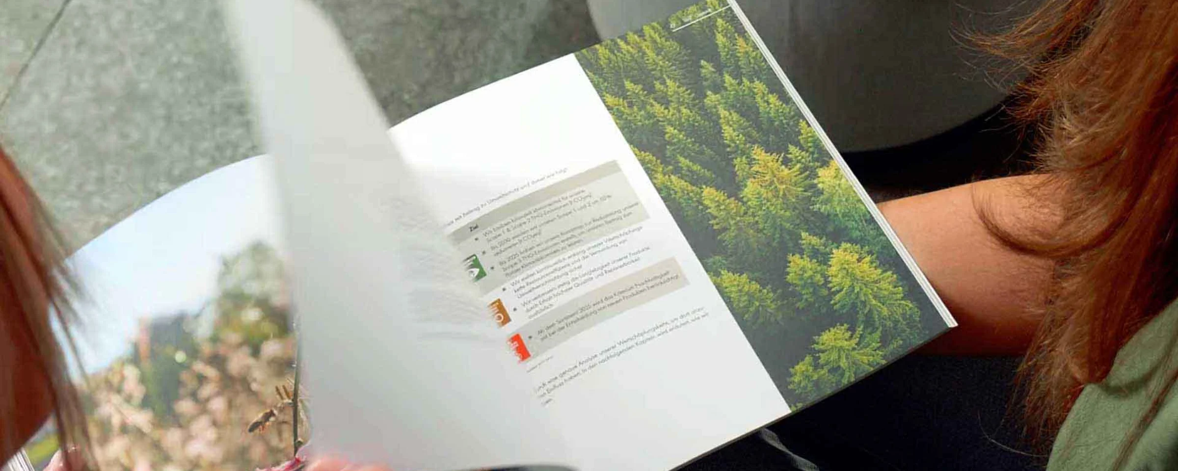 Due persone sfogliano una rivista di foto naturali sedute su un divano grigio. Nolte Kitchen.