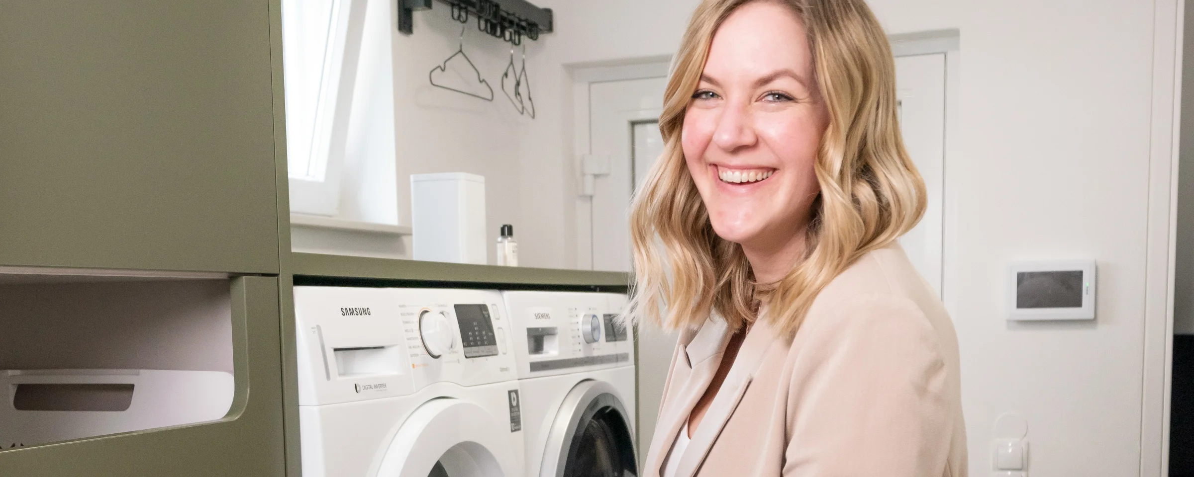 Una donna in una moderna lavanderia con lavatrice e asciugatrice di Nolte Utility Rooms.