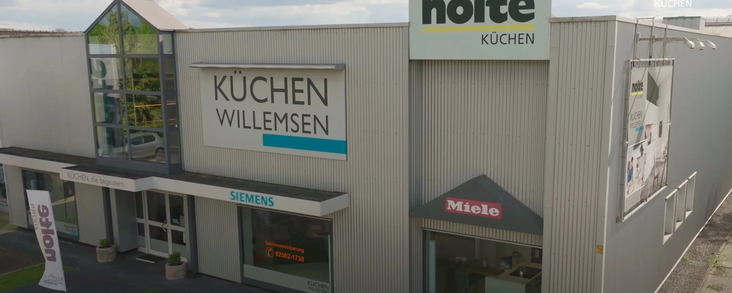 Edificio con carteles de Küchen Willemsen, Siemens y Miele, Nolte Kitchen al fondo.
