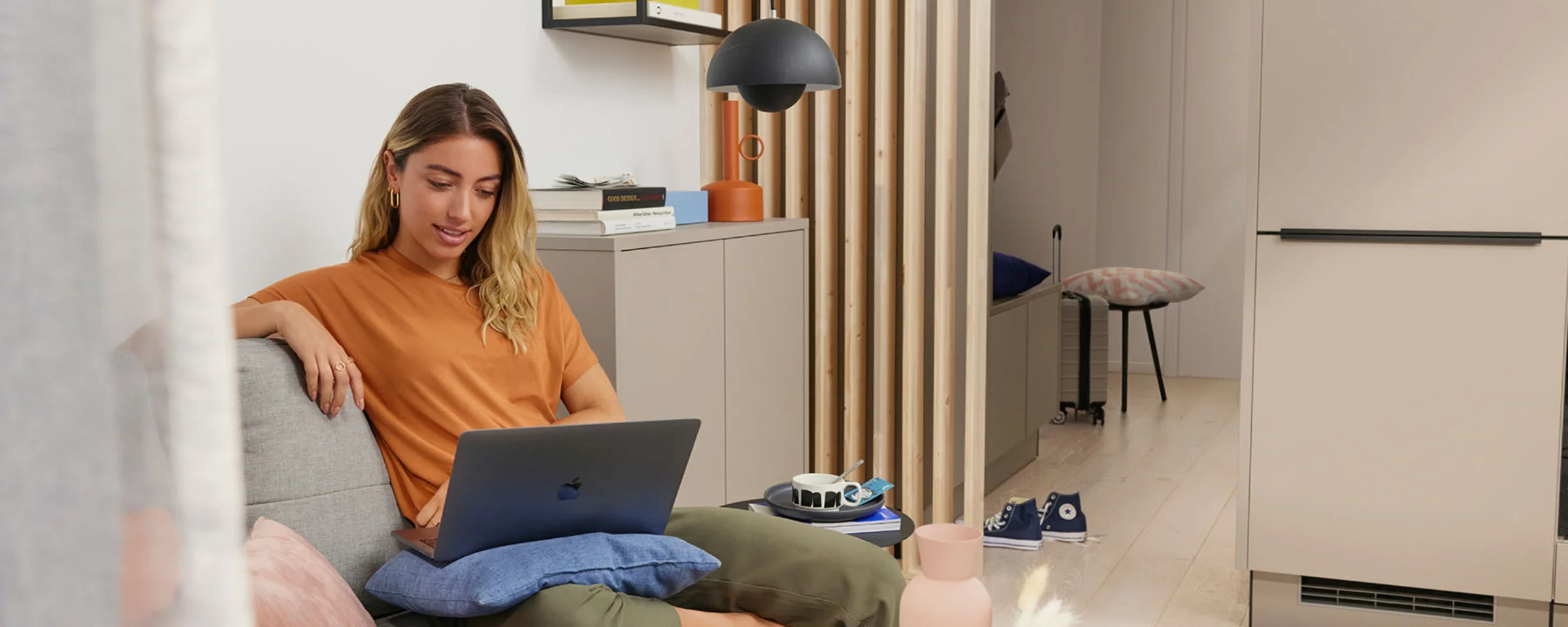 Una donna è seduta su un divano con un laptop in un soggiorno moderno. Nolte Living.