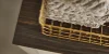 Cesto dorato con asciugamani su uno scaffale in legno scuro di Nolte Living.