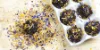 Una confezione di muffin al cioccolato decorati con fiori secchi su un tagliere di legno.