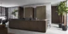 Esclusiva cucina Nolteneo con il pregiato frontale in legno neoLEAF in Noce Marone e l'elegante neoPURE in Metal Bronze. L'isola della cucina senza maniglie mostra un aspetto in vero legno con una venatura fine, mentre i pensili in tonalità bronzo metallico creano un contrasto elegante. Il design convince con linee chiare, materiali di alta qualità e un effetto spaziale lussuoso e aperto.