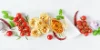 Due persone preparano insieme un pasto. Sul piano di lavoro della cucina vengono tagliate delle verdure e mescolata un'insalata.