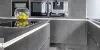 Cucina moderna con armadi grigi e ciotola di frutta sul piano di lavoro di Nolte Kitchen.