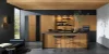 Moderna cucina Nolte con l'esclusiva frontale in vero legno neoNATURE in quercia Cottage. L'aspetto caldo del legno è elegantemente completato da accenti neri e scaffali aperti. L'isola della cucina con area salotto e il concetto di illuminazione ben studiato creano un'atmosfera accogliente con eleganza naturale.