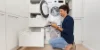 Ein Mann bedient eine Waschmaschine in einem modernen Nolte-Hauswirtschaftsraum.