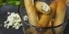 Involtini croccanti al formaggio su ardesia, decorati con erbe fresche.
