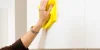 Una mano pulisce un armadio da cucina bianco di Nolte Kitchen con un panno giallo.