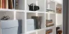 Scaffale con libri, fotocamera e scatole; esempio di elegante stoccaggio di Nolte Living.