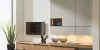 Soggiorno moderno con eleganti armadi e TV, decorato con piante e sculture, Nolte Living.