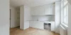 Cucina moderna e minimalista con armadi bianchi e pavimento in legno di Nolte Kitchen.