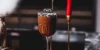 Un bicchiere di mousse al cioccolato con biscotti su un tavolo, sullo sfondo candele rosse.
