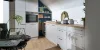 Cucina moderna con armadi bianchi e piano in legno sotto un tetto spiovente. Nolte Kitchen.