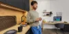 Un uomo in una cucina moderna con dettagli in legno e arredi neri, Nolte Kitchen.