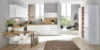 Helle Nolte cucina con il programma di frontali PLUS in bianco softmatt, combinato con piani di lavoro in legno e postazione di lavoro integrata in ambiente living aperto e pieno di luce.