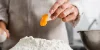 Una persona separa un tuorlo d'uovo sopra una montagna di farina in una cucina moderna di Nolte Kitchen.