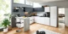 Moderna Nolte cucina in L-Form und banco con FEEL fronti in Arcticweiß softmatt e PLUS fronti in Schwarz softmatt. Il design senza maniglie è completato da un sorprendente bancone effetto cemento. L'effetto aperto e luminoso della stanza è sostenuto da molta luce naturale e materiali naturali come pavimento in legno e piante – uno spazio elegante e funzionale per cucinare e vivere.