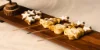 Su un vassoio di legno ci sono biscotti a forma di stella e dolci su spiedini.