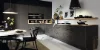 Cucina moderna con armadi scuri, tavolo da pranzo e decorazioni, progettata da Nolte Kitchen.