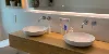 Bagno moderno con doppio lavabo e specchio, decorato con piante. Nolte SPA.