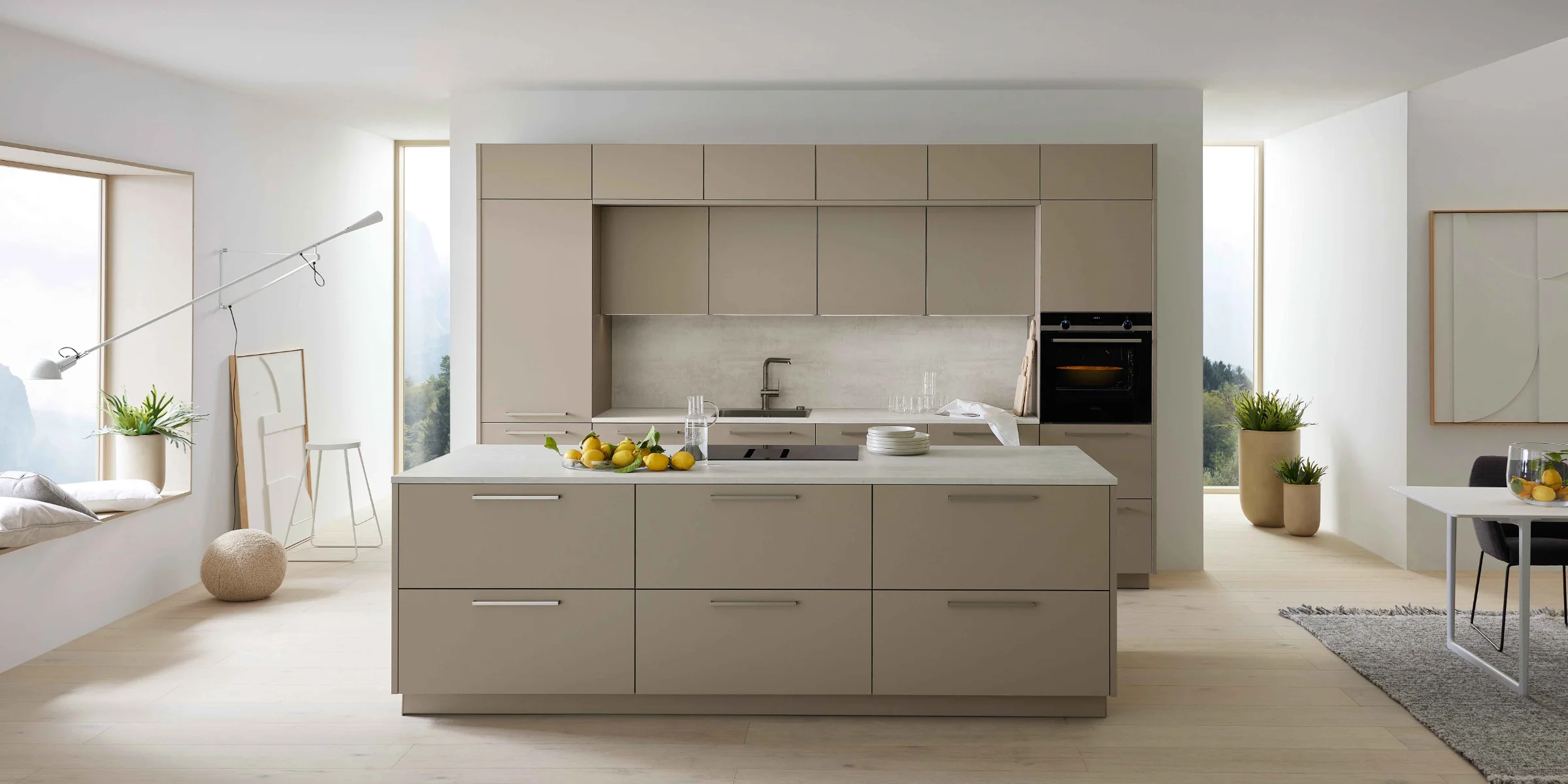 Cucina moderna con isola, armadi chiari e grandi finestre, progettata da Nolte Kitchen.