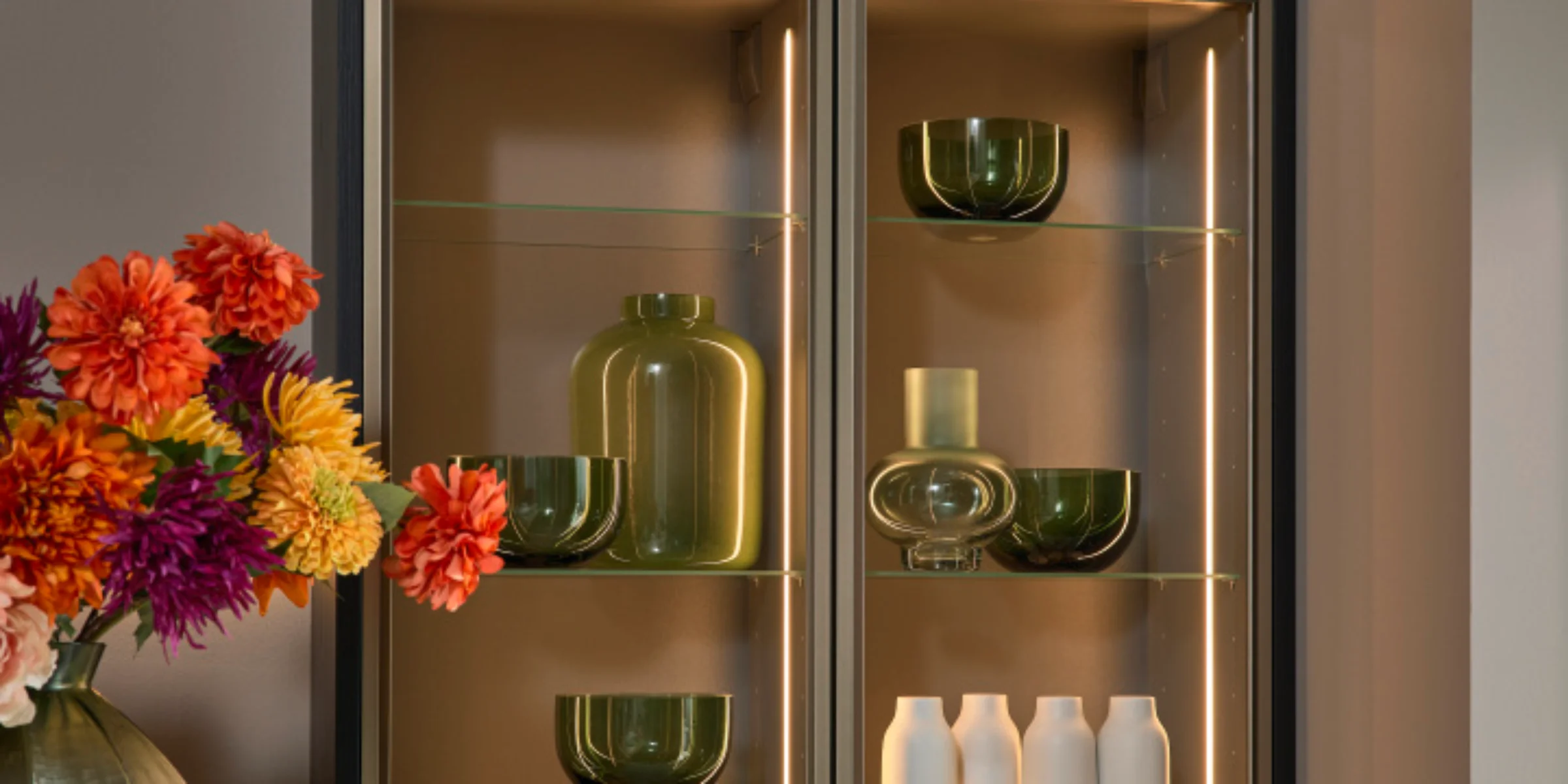 Elegante credenza da cucina con ripiani in vetro e illuminazione decorativa, progettata da Nolte Kitchen.