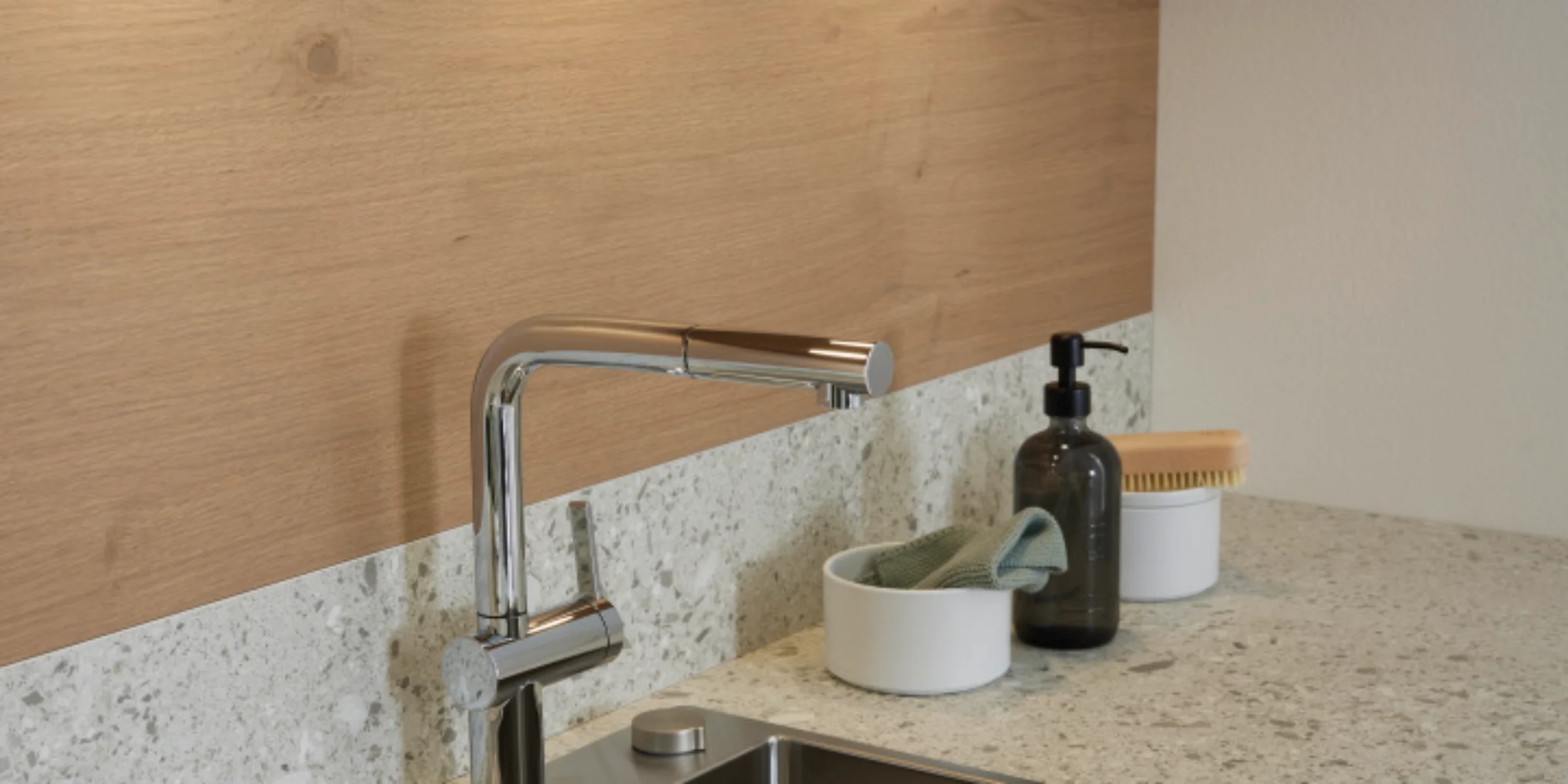 Lavello moderno con rubinetto e piano d'appoggio, circondato da legno e pietra. Nolte Kitchen.