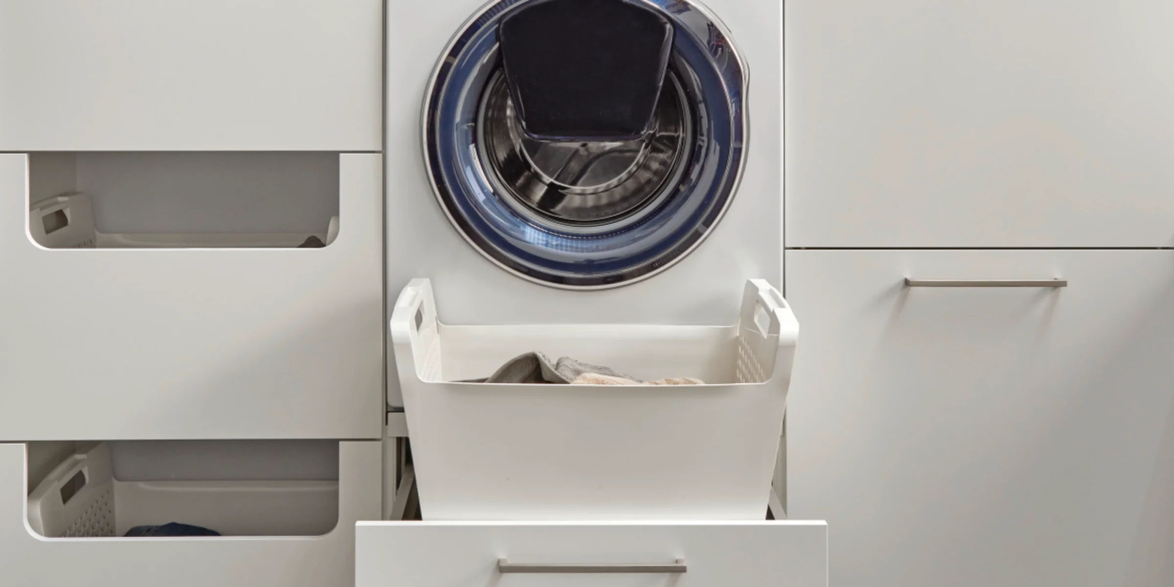 Una moderna lavanderia con lavatrice e spazio di archiviazione, progettata da Nolte Utility Rooms.