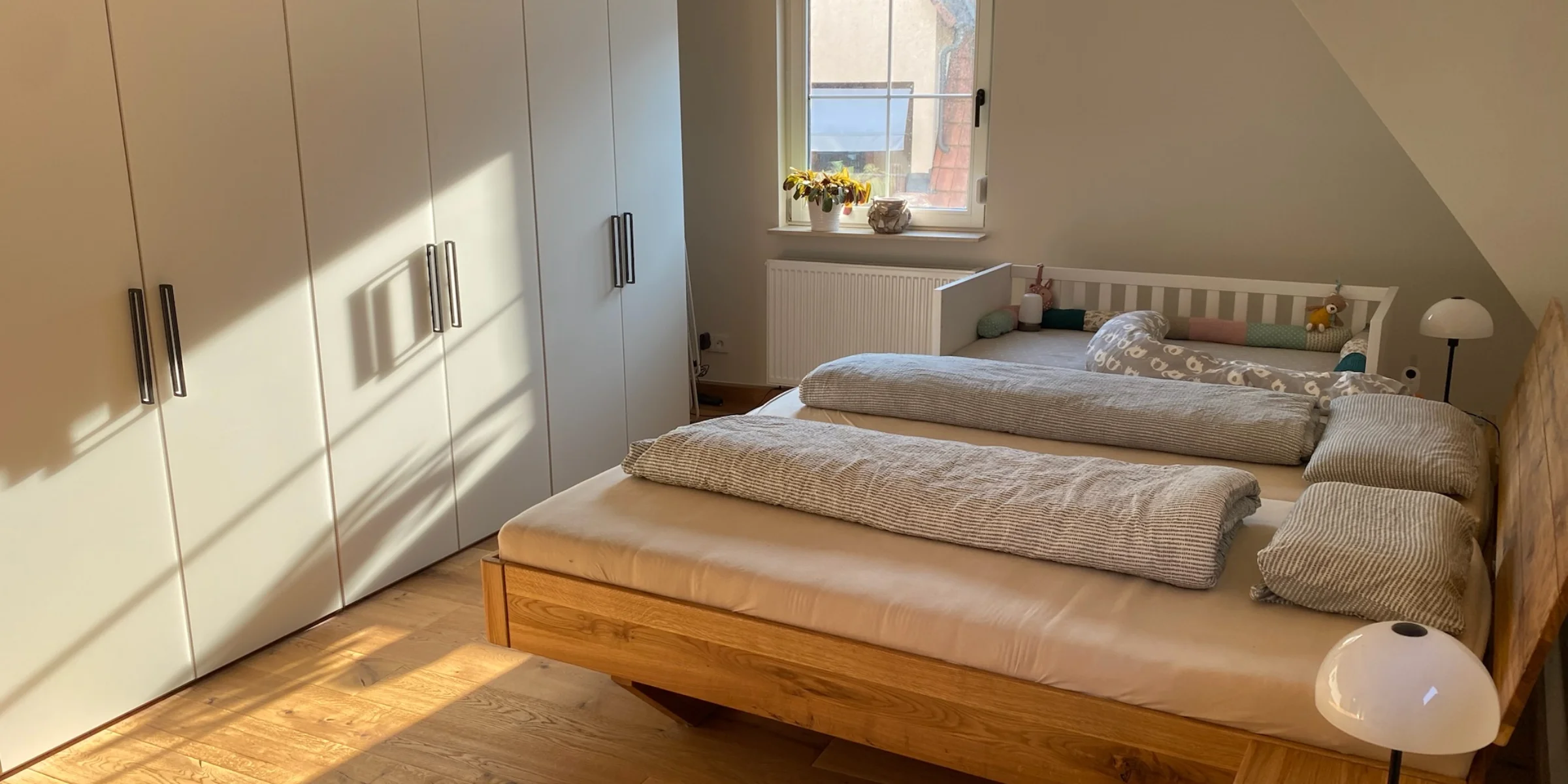 Camera da letto con letto matrimoniale e armadio, illuminata dalla luce solare, di Nolte Living.