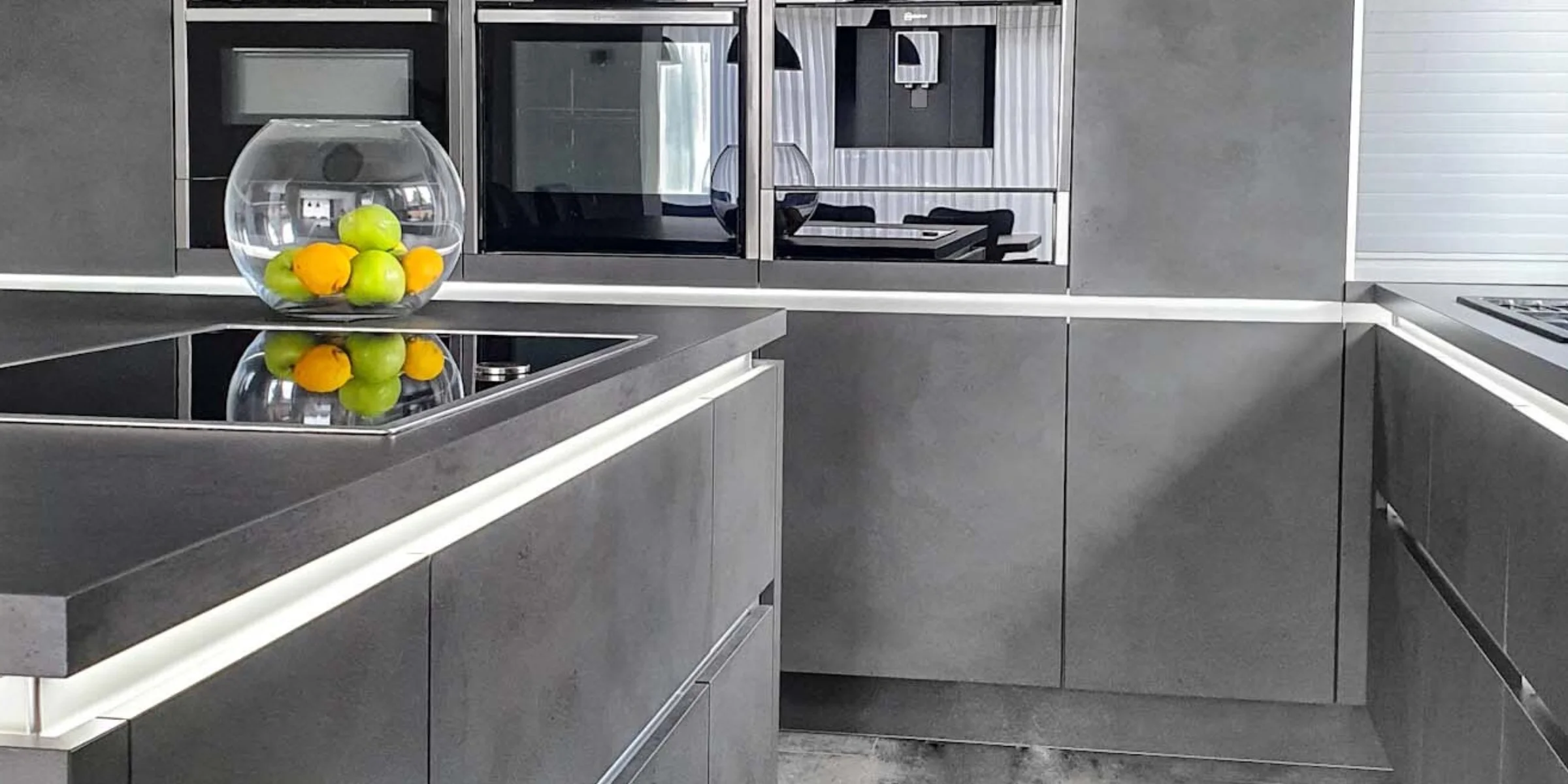 Cucina moderna con armadi grigi e ciotola di frutta sul piano di lavoro di Nolte Kitchen.