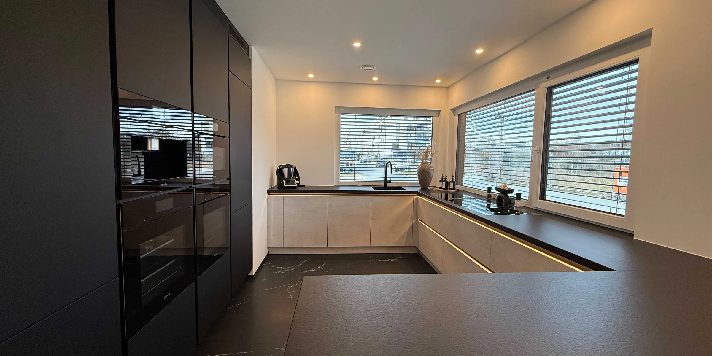 Modern kitchen with dark cabinets and large windows, Nolte Kitchen.
