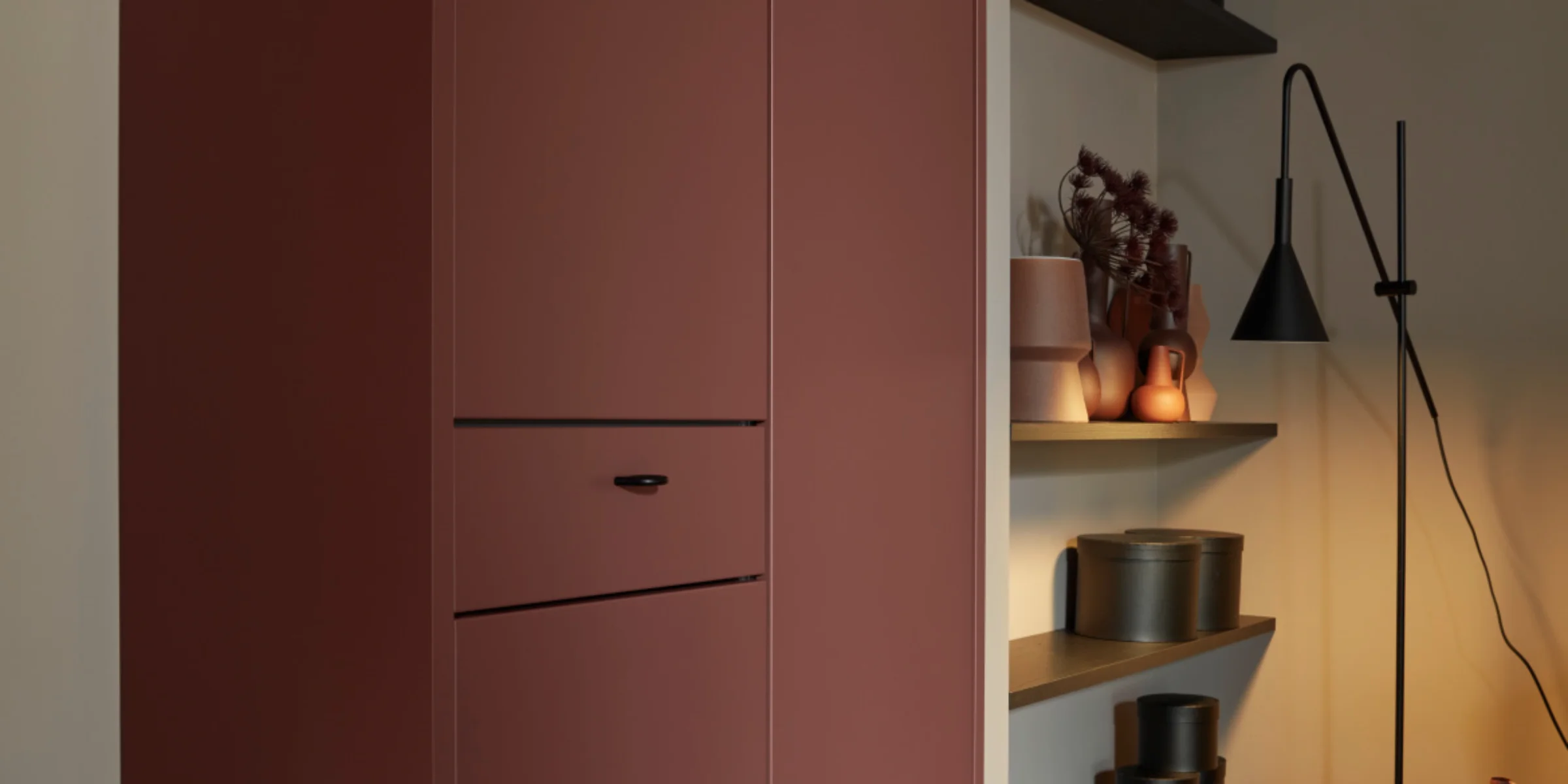 Un elegante soggiorno con armadi e scaffali rossi, illuminato, in stile Nolte Living.