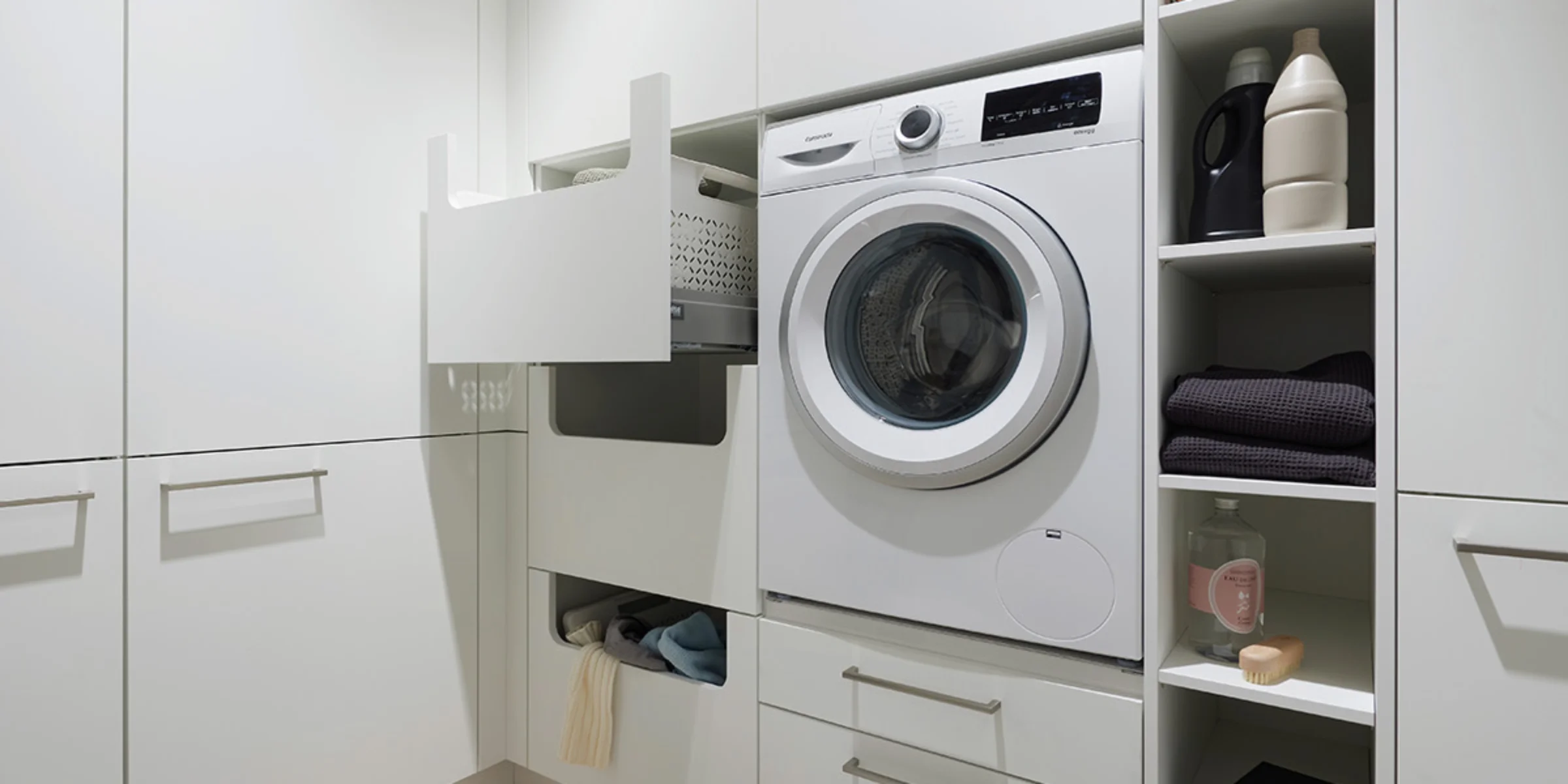 Moderna lavanderia con lavatrice e spazio di archiviazione, progettata da Nolte Utility Rooms.
