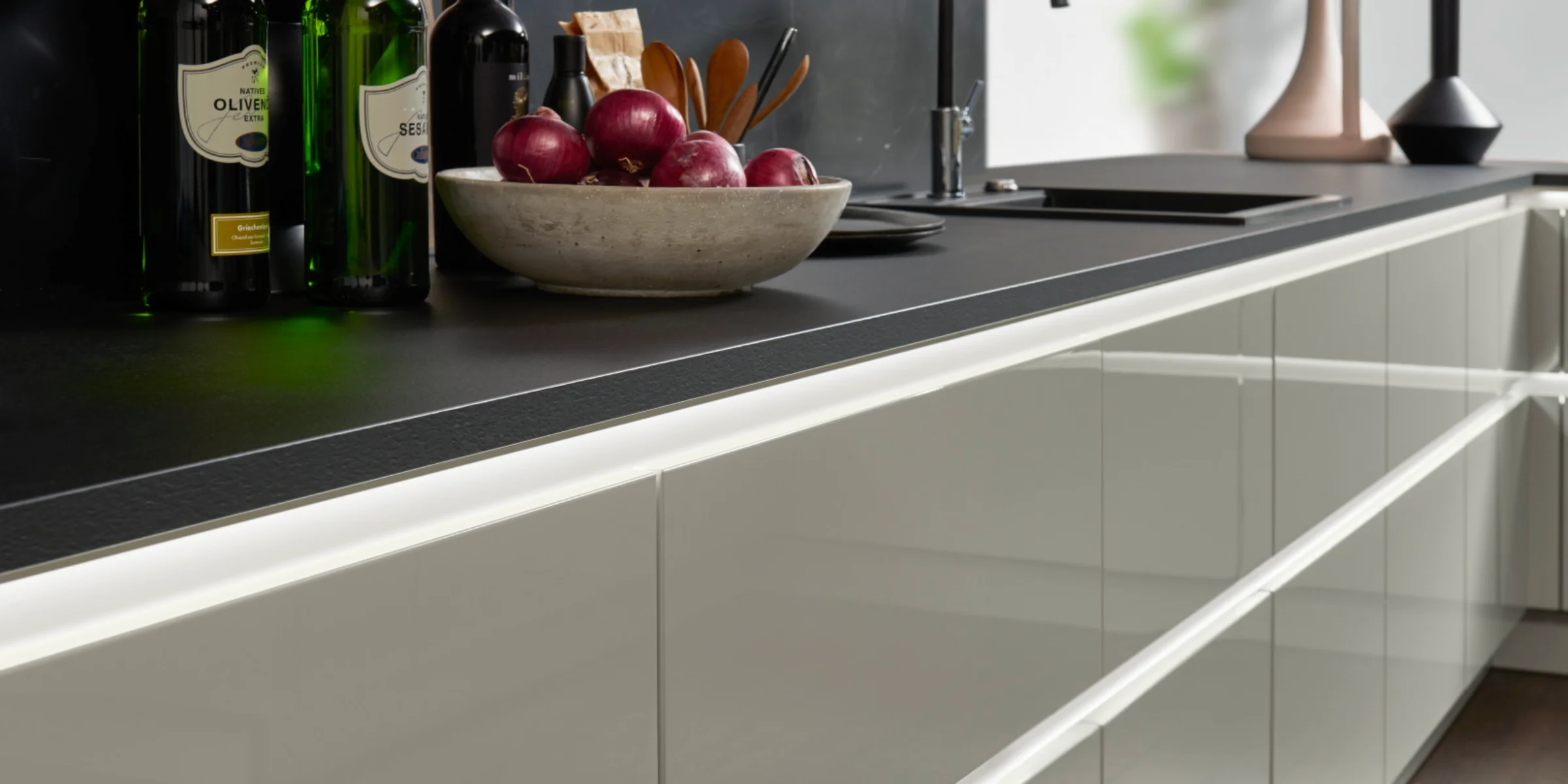 Cucina moderna con piani neri e eleganti armadi bianchi di Nolte Kitchen.