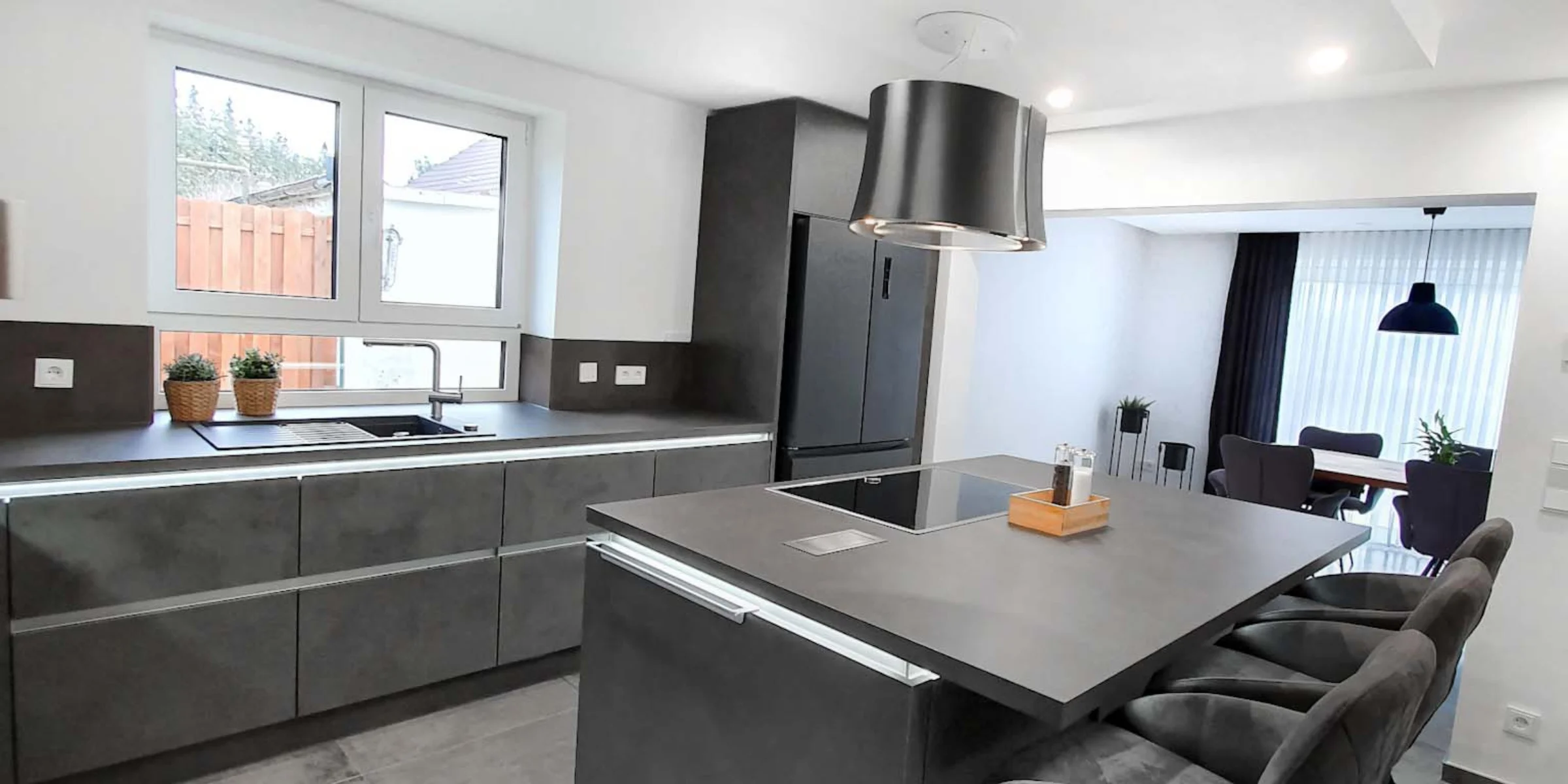 Cucina moderna con isola grigia e sgabelli in uno spazio aperto, Nolte Kitchen.