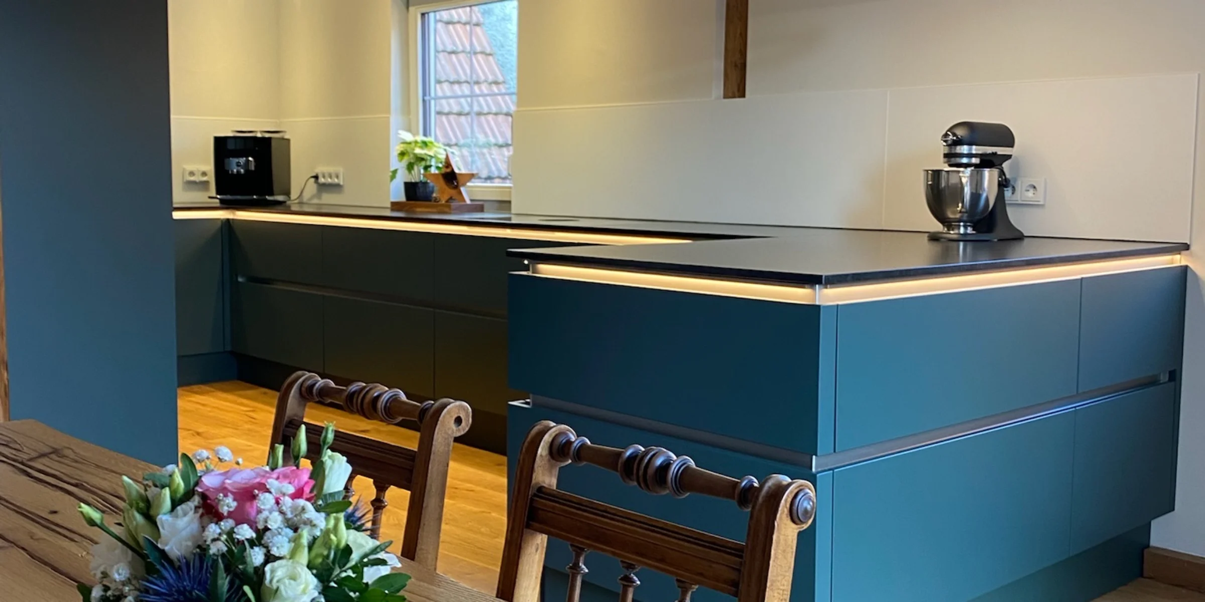 Cucina moderna con travi in legno e fiori sul tavolo, design di Nolte Kitchen.