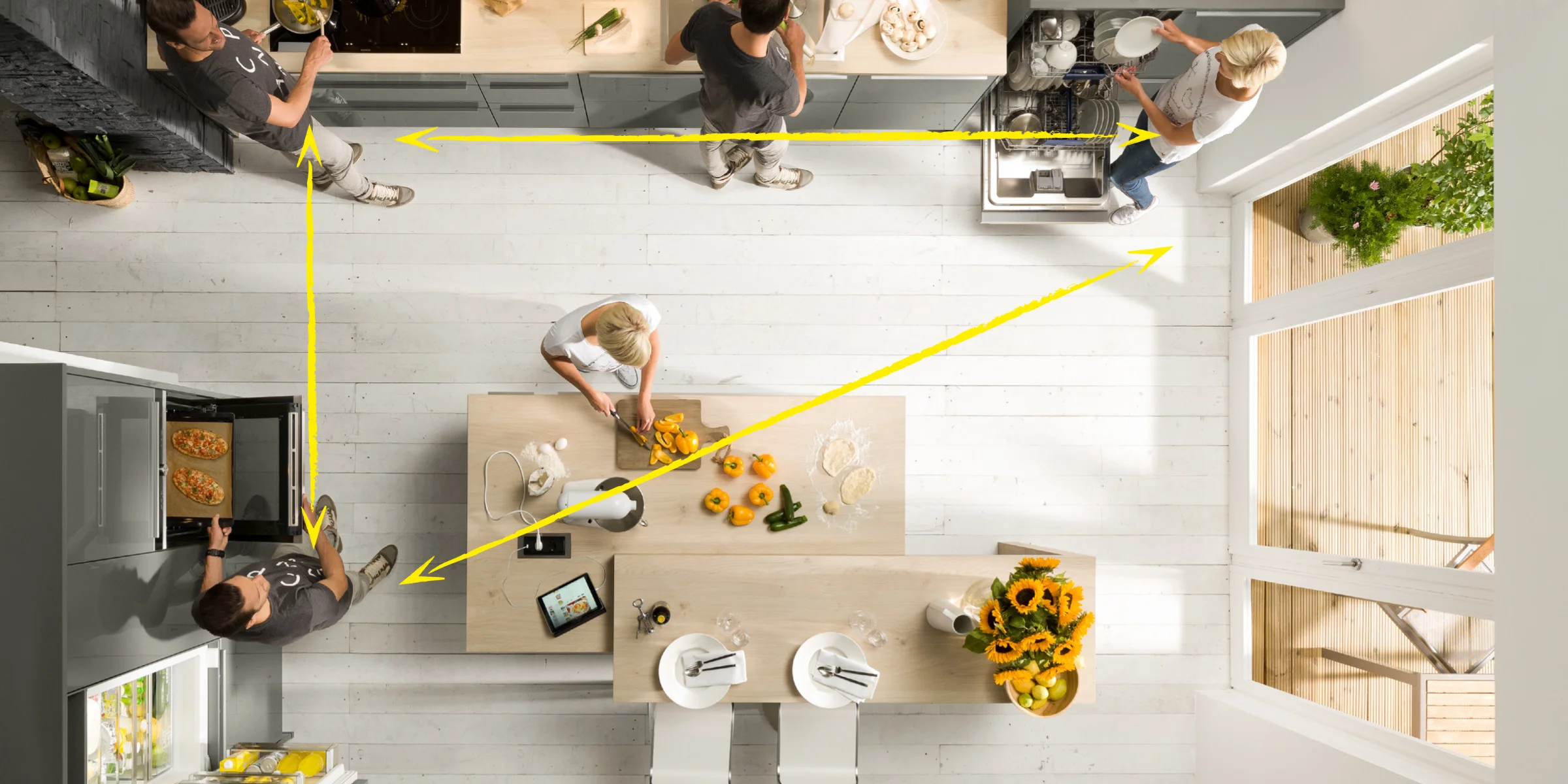 Modern kitchen with people cooking, equipped by Nolte Kitchen.