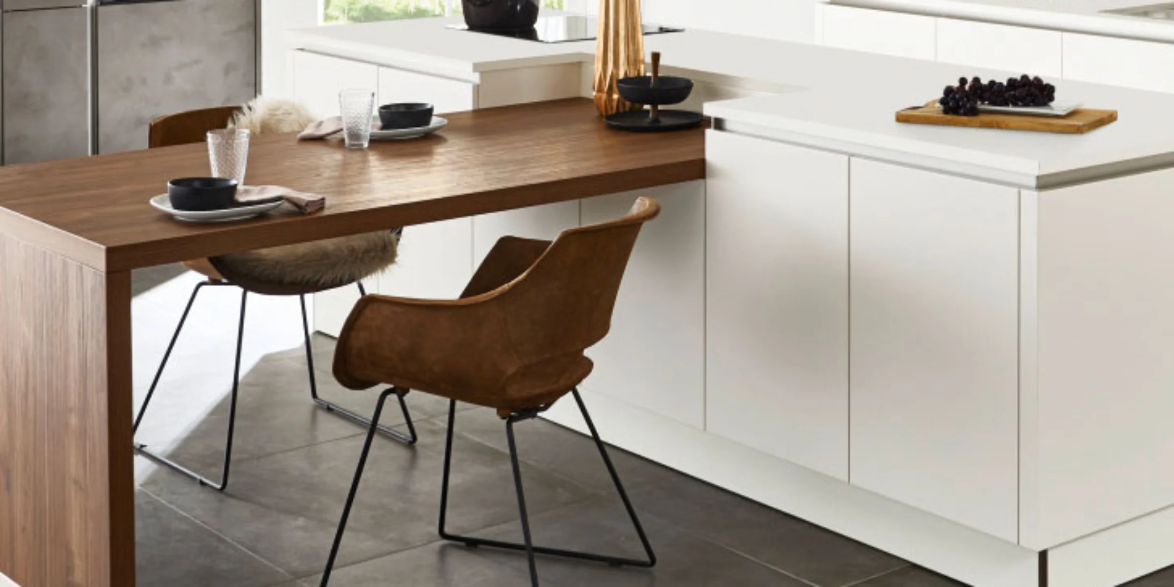 Cucina moderna con tavolo in legno e mobili bianchi, decorata con stoviglie e fiori. Nolte Kitchen.