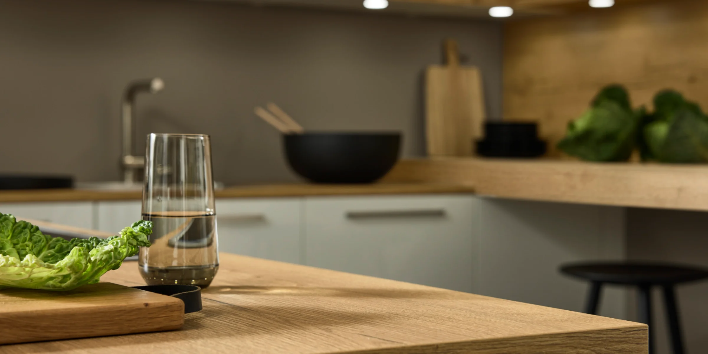 Cucina moderna con superfici in legno e insalata sul tavolo, design di Nolte Kitchen.