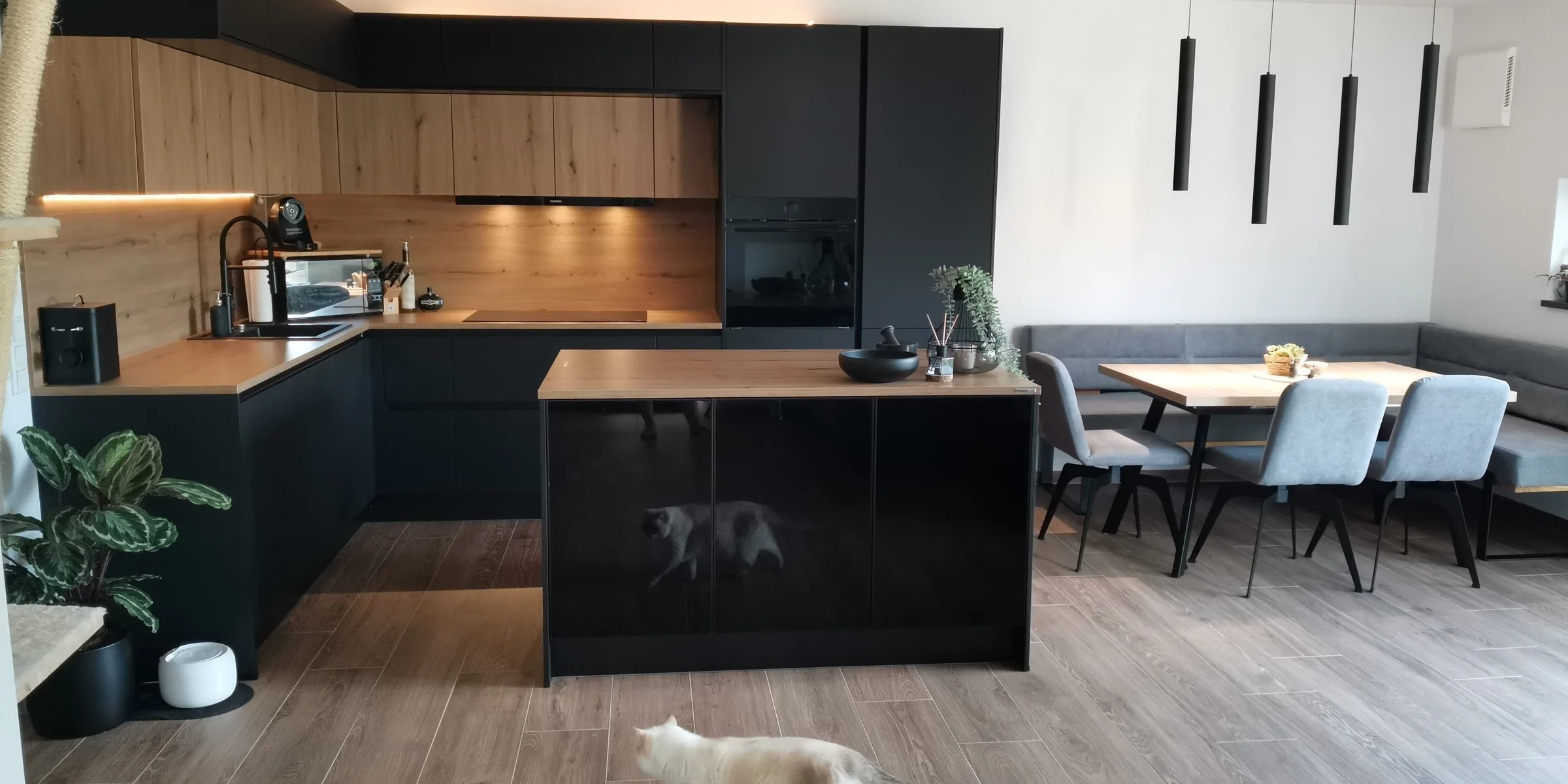 Cucina moderna con elementi in legno e nero, isola e tavolo; Nolte Kitchen.