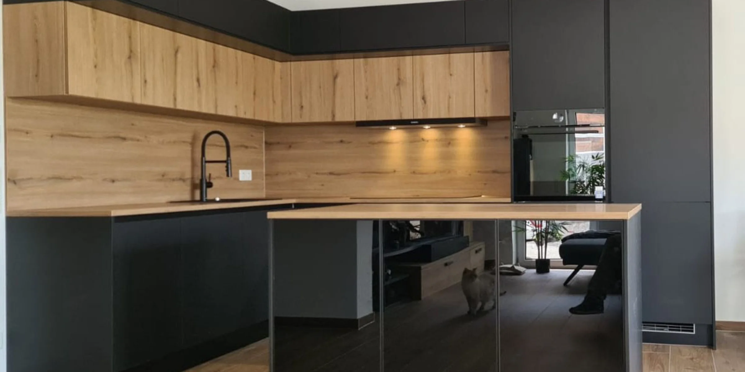 Cucina moderna con frontali scuri e in legno e un'isola di cottura di Nolte Kitchen.