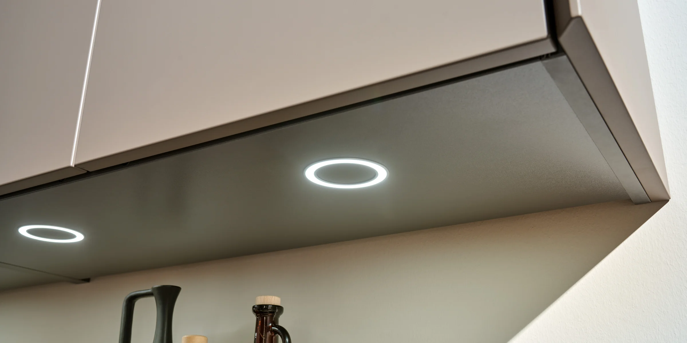Bottiglie sotto un pensile illuminato; cucine Nolte.